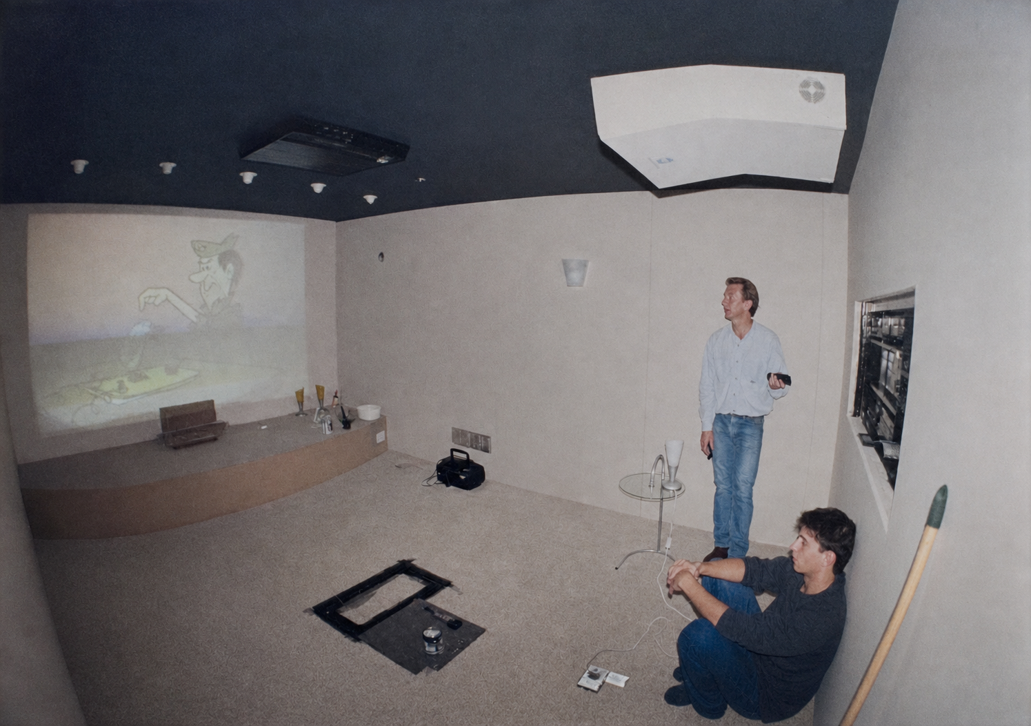 Simon at nineteen sitting on the floor of a home cinema build with his dad, projector running a cartoon on the wall