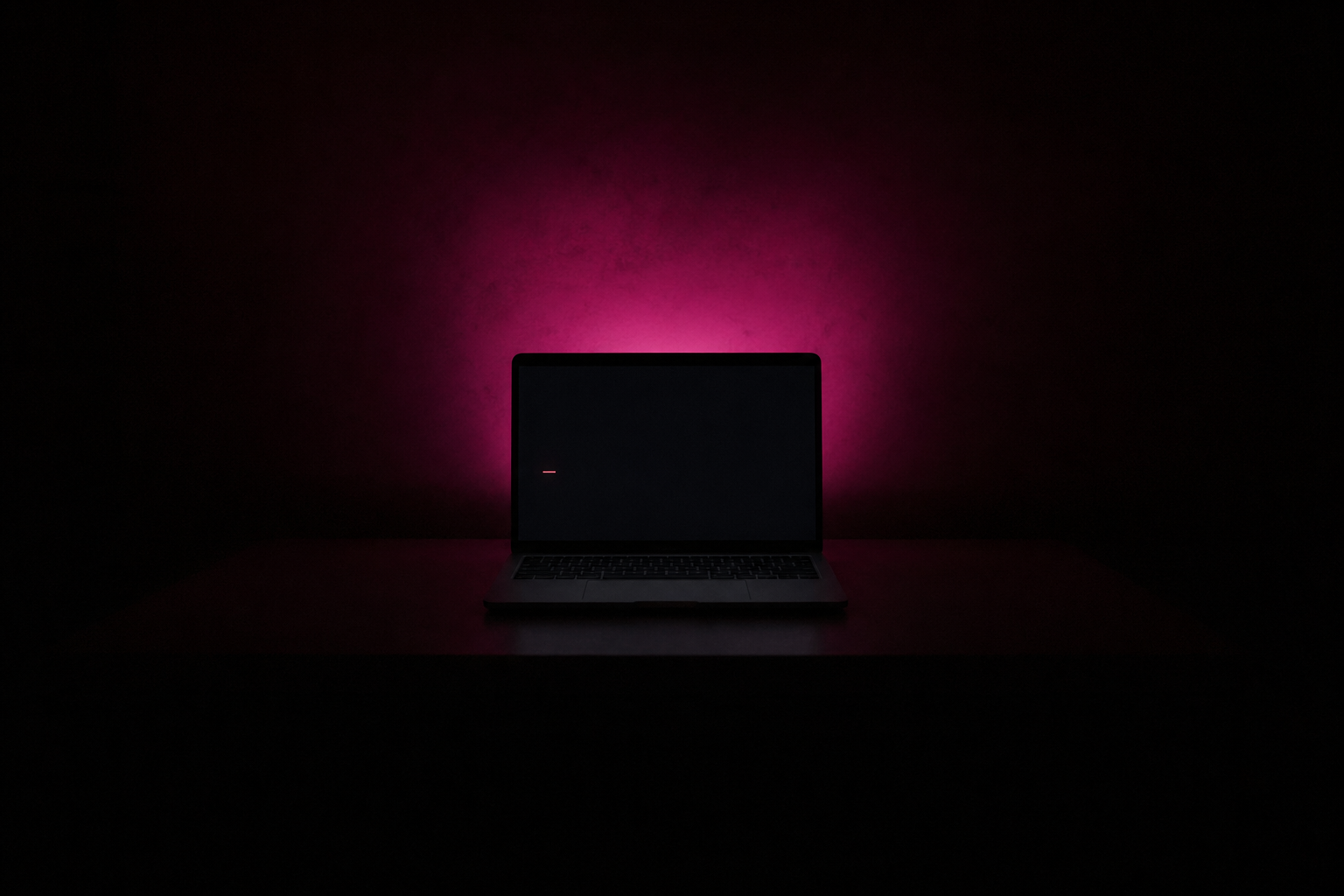 A laptop screen in a dark room showing only a single thin red line of text